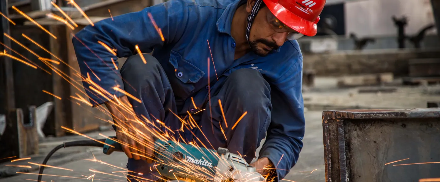 Maihan Steel worker grinding a steel part, sparks flying
